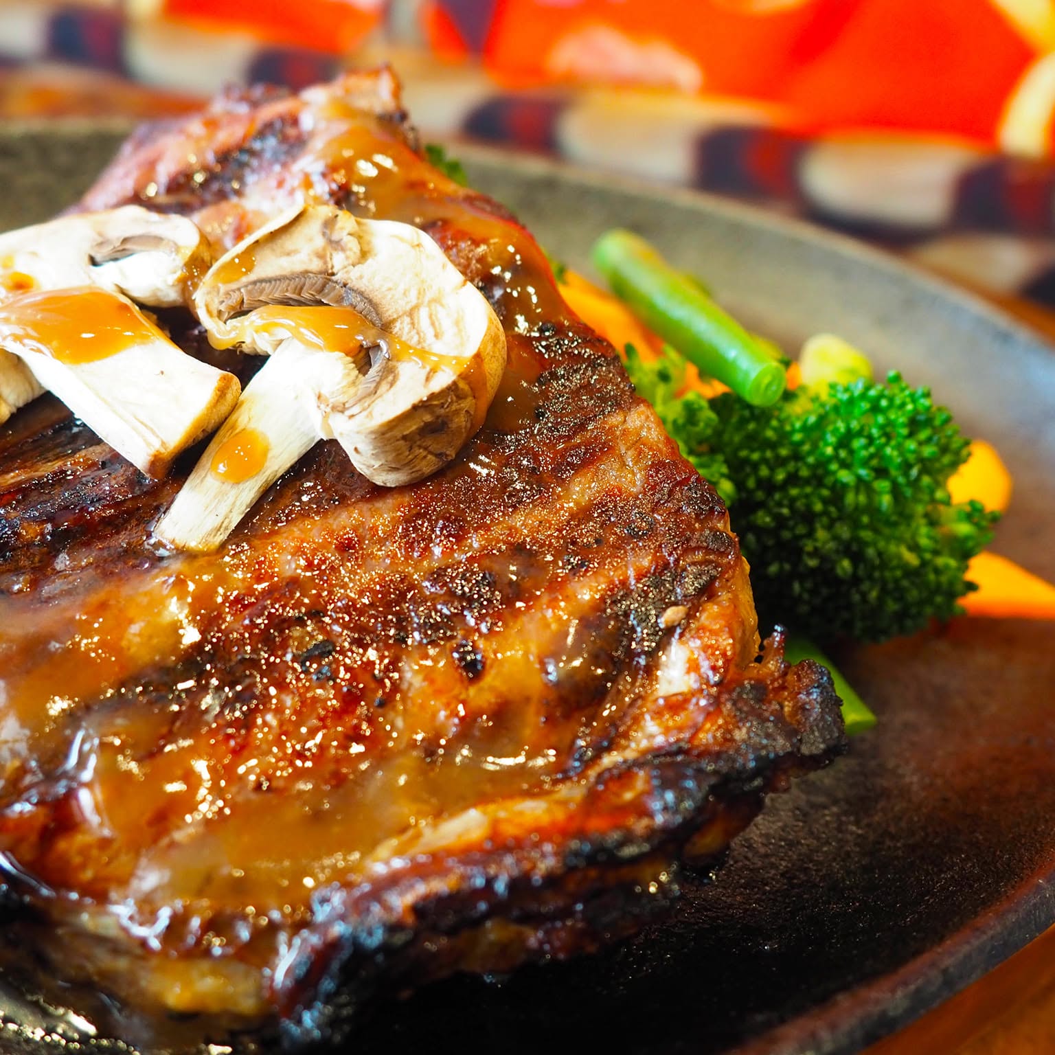 Grilled meat on a sizzling plate with mushroom gravy and broccoli