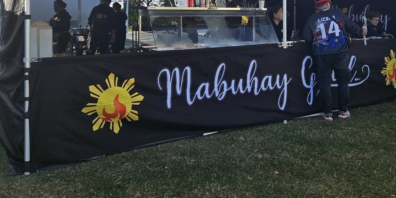 Customers ordering at the Mabuhay Grill marquee with its Philippine sun logo